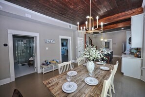 A dining area with a wooden table set for four, a chandelier, and a sign that reads 'STAY'. - Coastal Cove Near Beach (Galveston)