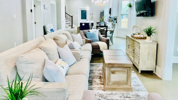 A living room with a sofa, coffee table, TV, and a staircase leading to another room. - Coastal Cove Near Beach (Galveston)