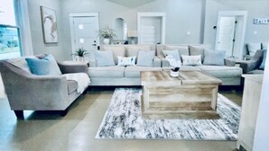 A living room with a sofa, armchair, coffee table, and a rug. - Coastal Cove Near Beach (Galveston)