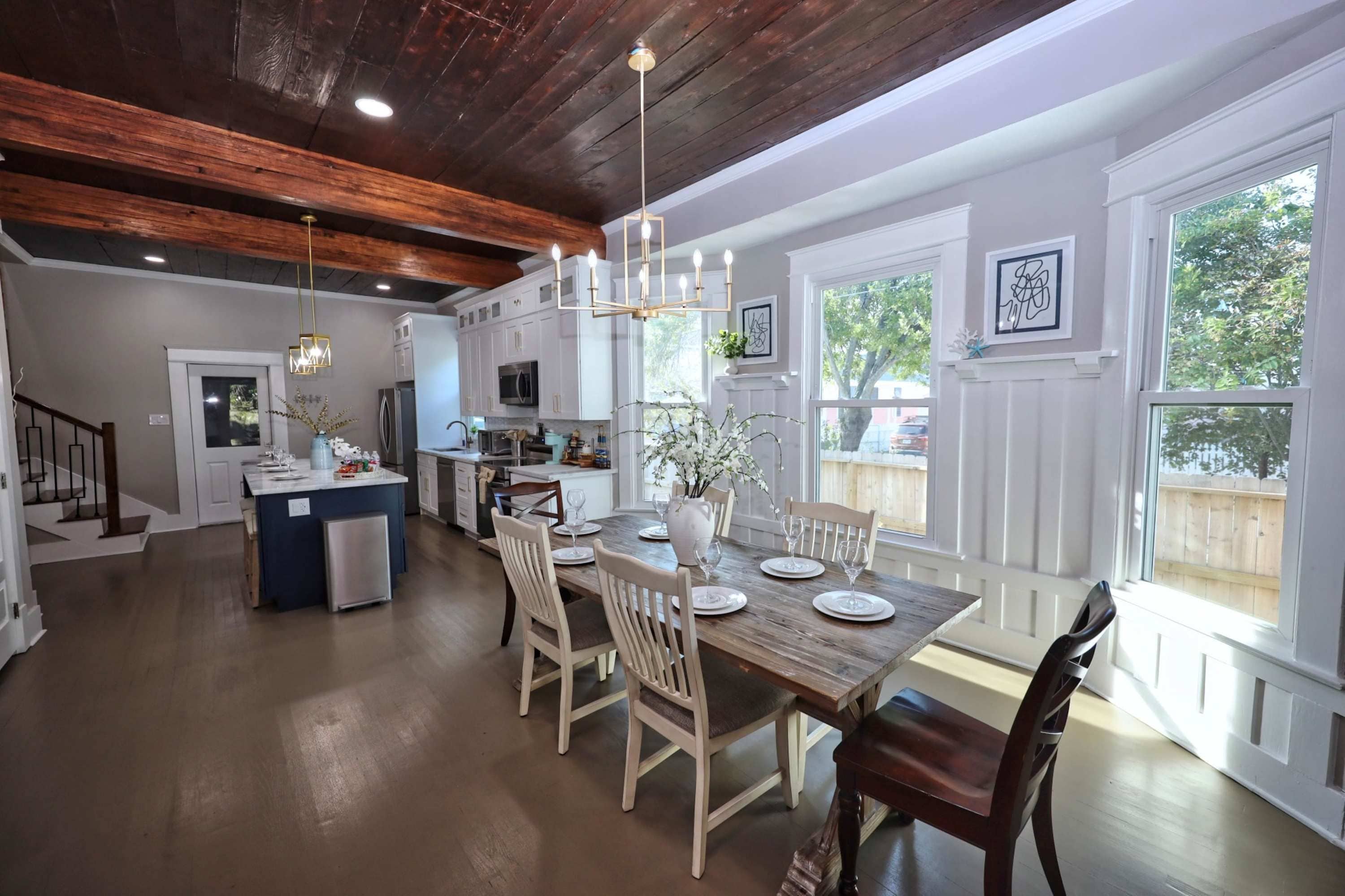 A spacious kitchen with a central island, white cabinetry, and a dining area with a wooden table and chairs.