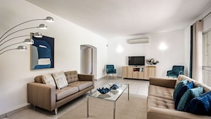 Un salon moderne avec un canapé, une table basse et un téléviseur.