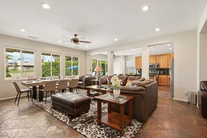 Una sala de estar amplia con comedor, cocina y ventilador de techo.