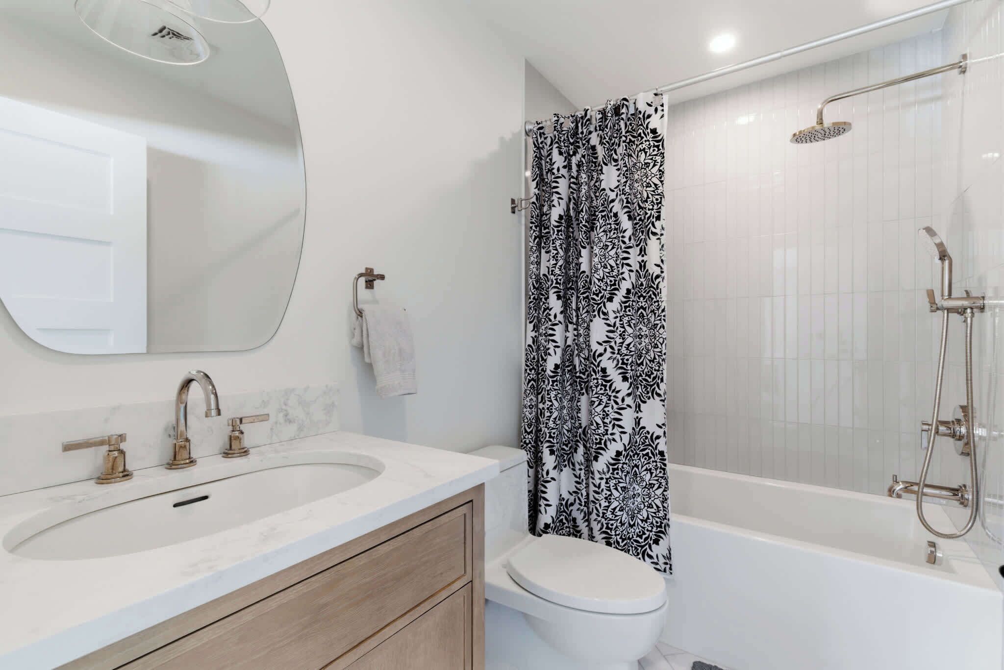 A bathroom with a sink, toilet, shower, and a mirror.