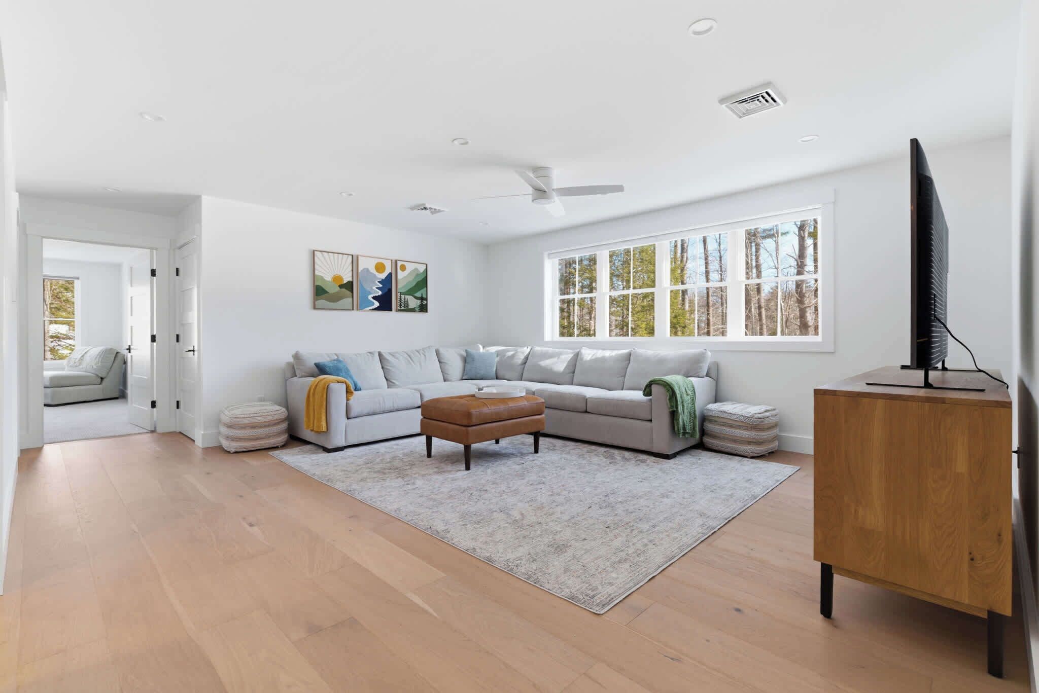 Un salon moderne avec un canapé, un pouf et un meuble en bois.