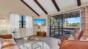 A spacious living room with a large sliding glass door leading to an outdoor area, a comfortable seating arrangement, and a painting on the wall. - Heavenly Par-adise 2‑Bedroom Villa Overlooking the Golf Course Seascape (Miramar Beach)