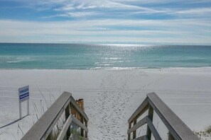 A beach with a wooden walkway leading to the water, a sign indicating it's a private beach, and footprints in the sand. - Heavenly Par-adise 2‑Bedroom Villa Overlooking the Golf Course Seascape (Miramar Beach)