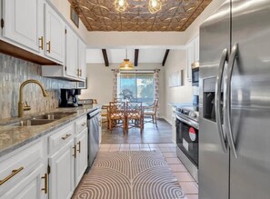 A modern kitchen with white cabinets, a stainless steel refrigerator, and a dining area with a table and chairs. - Heavenly Par-adise 2‑Bedroom Villa Overlooking the Golf Course Seascape (Miramar Beach)