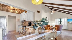 A modern kitchen with white cabinets, a dining area with a glass table, and a living room with a sofa and a large plant. - Heavenly Par-adise 2‑Bedroom Villa Overlooking the Golf Course Seascape (Miramar Beach)