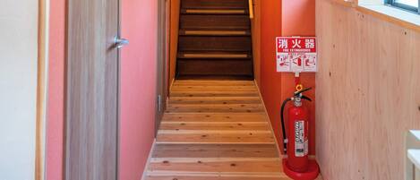 A wooden staircase in a hallway with a fire extinguisher mounted on the wall.