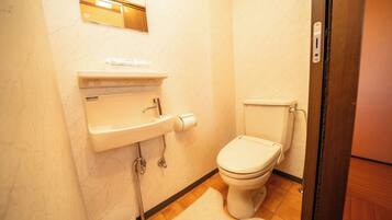 A bathroom with a toilet, sink, and mirror.