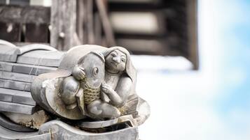 Une sculpture en pierre représentant une figure tenant un poisson, placée sur un toit.