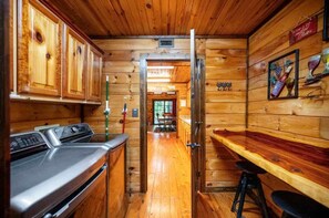 Ein Holzblockhaus mit Küchenzeile, einer Bar und einem Essbereich.