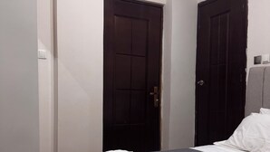Un dormitorio con una cama, dos puertas y una mesita de noche.