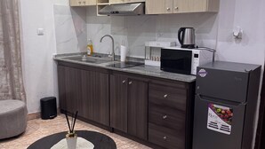 Una cocina moderna con microondas, refrigerador y un pequeño comedor con mesa redonda.