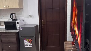 Una kitchenette equipada con microondas, refrigerador y pequeña cafetera.