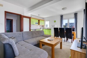 Ein Wohnzimmer mit einer Couch, einem Holztisch und einem Essbereich mit Tisch und Stühlen.