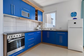 A kitchen with blue cabinets, a white refrigerator, and a built-in oven. - Kotari Sukošan in Sukošan - Nord-Dalmatien / Kotari Sukošan in Sukošan - Appartement für 4 Personen AP2 (Sukosan)