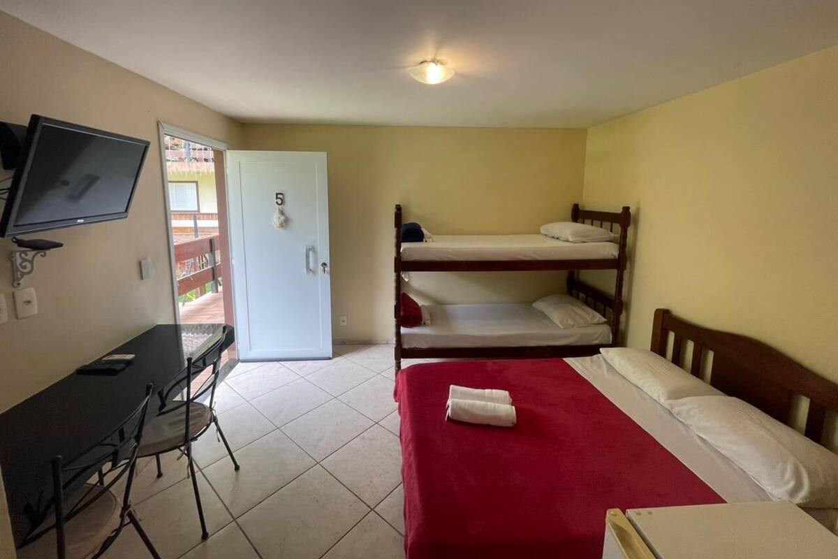 A room with bunk beds, a desk, and a television.