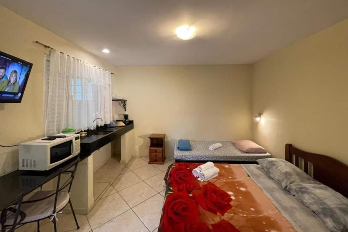 A hotel room with a bed, a desk with a computer, a microwave, and a TV.