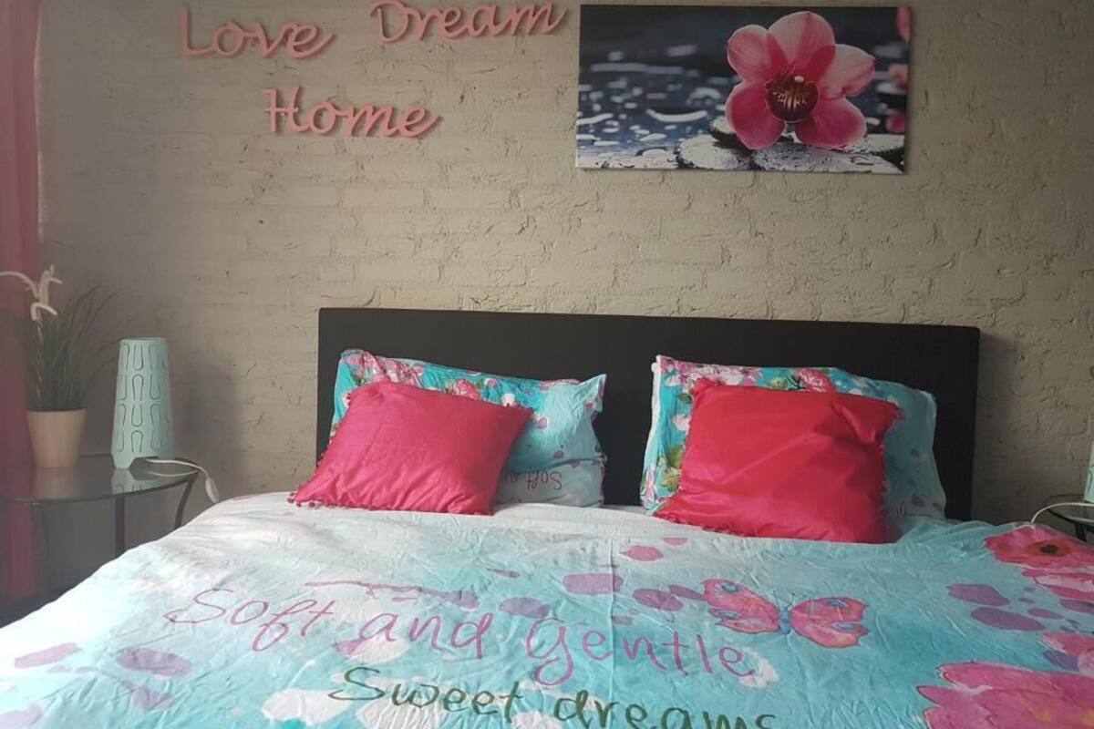 Ein Schlafzimmer mit einem Bett, zwei Kissen, einer Wand mit einem Blumenbild und einer Wand mit einem Hinweisschild.
