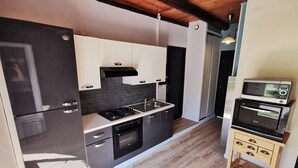 Uma cozinha moderna com armários em preto e branco, forno embutido e micro-ondas sobre um suporte de madeira.