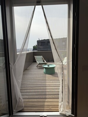 A balcony with a mosquito net, a green table, and a lounge chair. - Duplex Rooftop 80m² with terrace Eiffel Tower view (Paris)