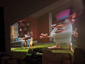 A room with a television displaying animated characters, a couch, and a shelf with items. - Duplex Rooftop 80m² with terrace Eiffel Tower view (Paris)