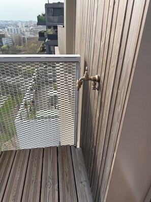 A balcony with a mesh screen, a metal faucet, and a wooden railing. - Duplex Rooftop 80m² with terrace Eiffel Tower view (Paris)