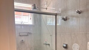 Un baño moderno con ducha envuelta en vidrio, inodoro y lavamanos.