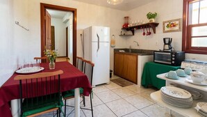 Una cocina compacta con refrigerador, estufa y microondas. Hay una mesa de comedor con sillas y una pequeña isla con pileta.