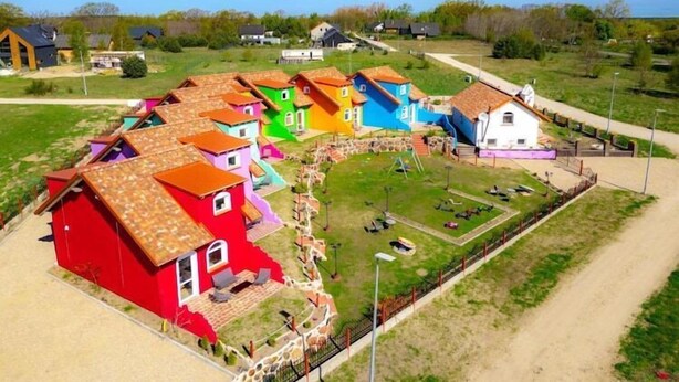 Un gruppo di case colorate con un'area verde e un sentiero sterrato.