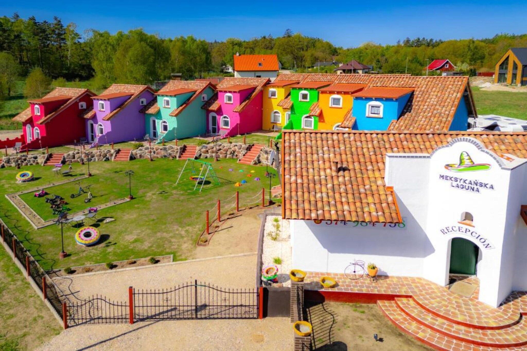 A colorful village with a reception building and a playground.