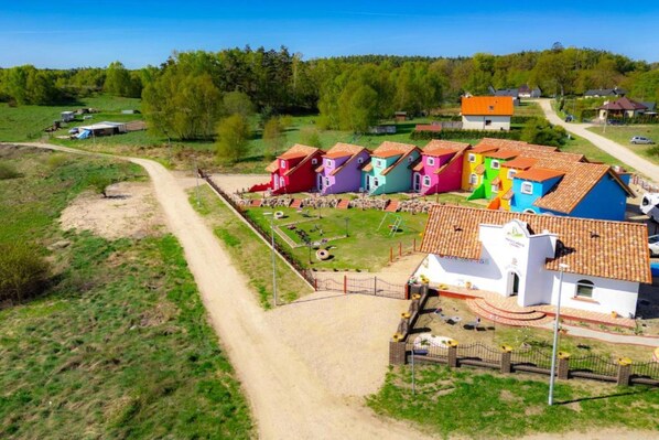 A rural area with colorful houses, a dirt road, and a fenced playground.