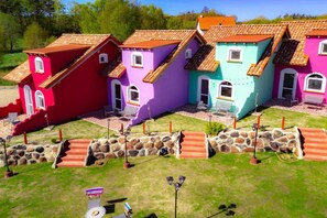A row of colorful houses with tiled roofs, stone walls, and a grassy lawn. - Mexican-themed holiday homes (Debina)