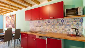 Eine Küche mit roten Schränken, einer Holz Arbeitsplatte, einer gefliesten Rückwand und einer Mikrowelle.