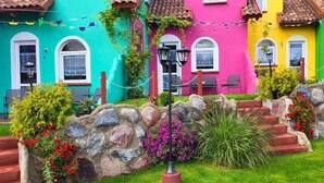 Une rangée de maisons aux couleurs vives, dotées de murs en pierre et d’un jardin bien entretenu.