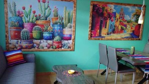 Une pièce comprenant un canapé, une table à manger avec des chaises et deux tableaux accrochés au mur.
