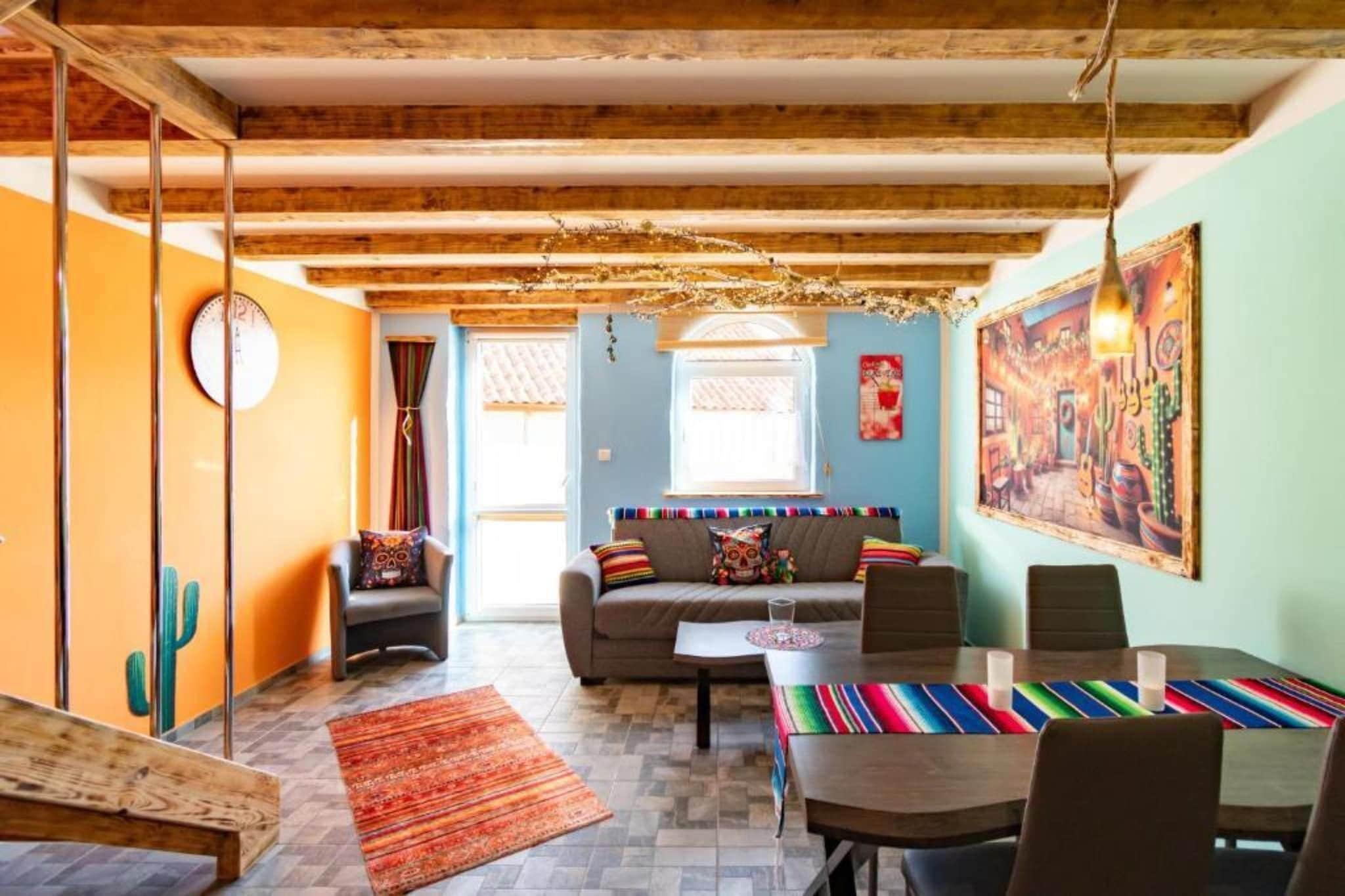 A cozy living room with a sofa, coffee table, and chairs, a dining table with chairs, and a large painting on the wall.