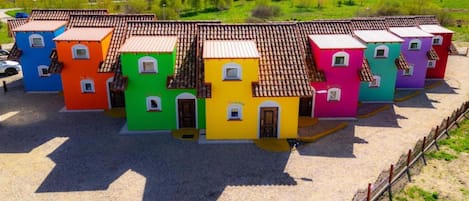 A row of colorful, single-story buildings with tiled roofs, arranged in a row.