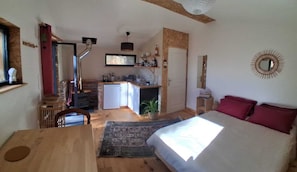 Une chambre de taille modeste comprenant un lit, un bureau, une petite kitchenette et une salle de bain.