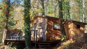 A cabin with a deck and a small window, surrounded by trees. - Isolated cabin in the forest (Lespinassière)