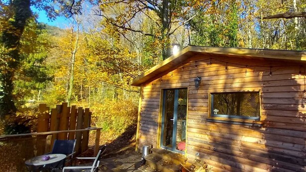 A wooden cabin with a door, a window, and a small porch area. - Isolated cabin in the forest (Lespinassière)