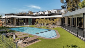Un hôtel moderne doté d’une piscine, d’un espace extérieur aménagé et d’une pelouse bien entretenue.