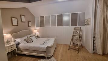 Un dormitorio con cama, mesitas de noche, una escalera, una ventana con persianas y una lámpara en el techo.