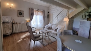 A cozy living room with a sofa, chairs, a table, a staircase, and a radiator. - Mas des Trois V - View Vignes & Ventoux - Gîte de Charme Premium 2 to 4 Adults (Sarrians)