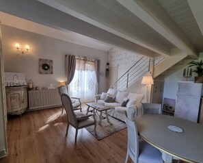 A cozy living room with a sofa, chairs, a table, a staircase, and a radiator. - Mas des Trois V - View Vignes & Ventoux - Gîte de Charme Premium 2 to 4 Adults (Sarrians)