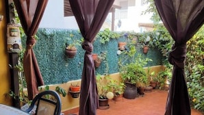 An outdoor patio with a table and chairs, surrounded by potted plants and draped curtains. - Apartment With Large Terrace in Almeria (Vera)