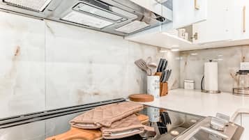 A modern kitchen with a stainless steel range, a marble backsplash, and a wooden cutting board.