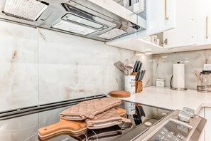 A modern kitchen with a stainless steel range, a marble backsplash, and a wooden cutting board.