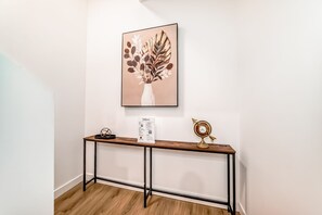 Ein Empfangsbereich mit einem Holztresen, einem gerahmten Kunstwerk, einem Willkommensschild und einer Zieruhr.